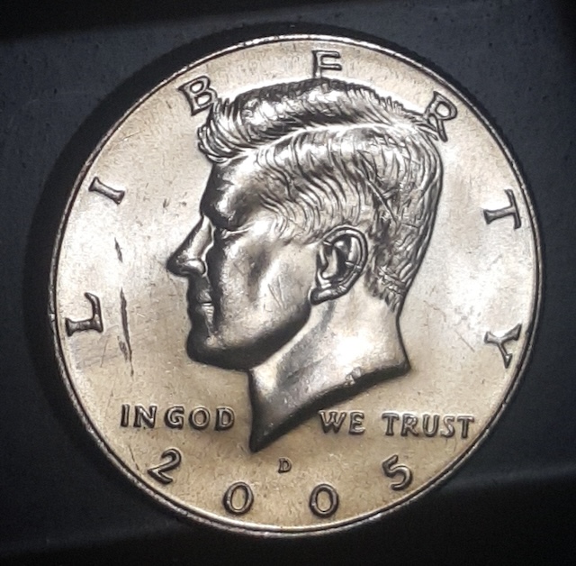 2005 Kennedy half dollar off-center strike error showing design shifted 30% off-center with visible date